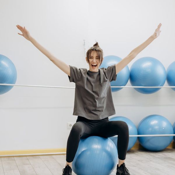 Woman smiling and stretching in a bright, sunlit room.
